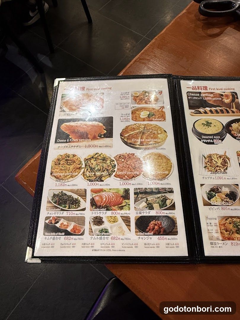 A close-up of an open menu book on a wooden table, featuring various Japanese dishes with prices in yen.