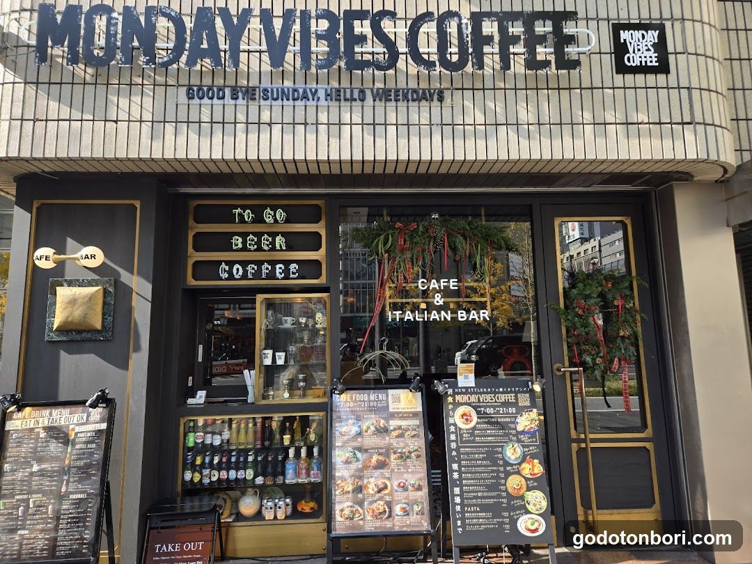 Exterior of Monday Vibes Coffee shop with signage reading 'Good bye Sunday, hello weekdays' and 'Cafe & Italian Bar'. Decorative wreaths on doors.