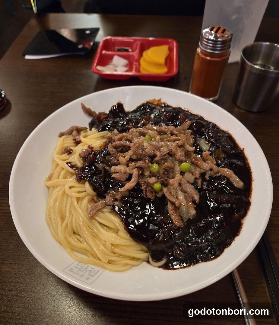 Bowl of noodles with dark sauce and meat