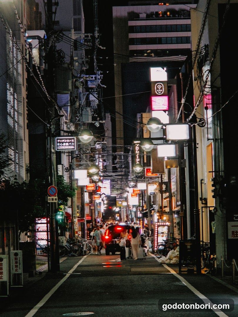 Night street scene with illuminated signs and pedestrians