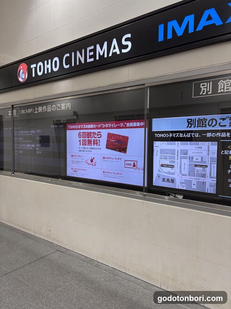A storefront of TOHO CINEMAS with an IMAX sign above the entrance. The facade features large glass windows displaying promotional posters and a map of the cinema layout. One poster advertises a special offer for six screenings, while another highlights the IMAX experience.