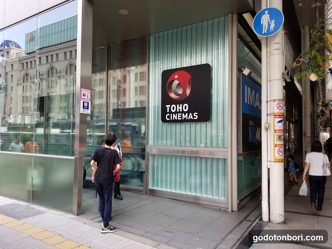Exterior view of Toho Cinemas storefront with visible signage, glass entrance, and pedestrians nearby.