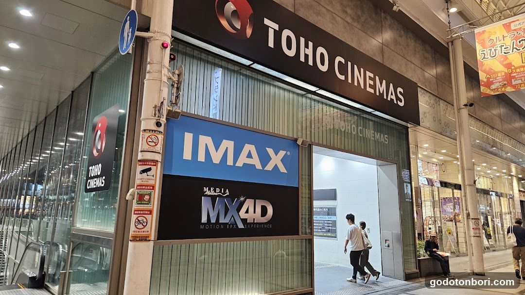 Exterior storefront of TOHO CINEMAS featuring prominent signage including 'IMAX' and 'MX4D Media Motion Picture Experience'. The entrance is visible with people walking by, and the building facade includes glass panels and illuminated signs.