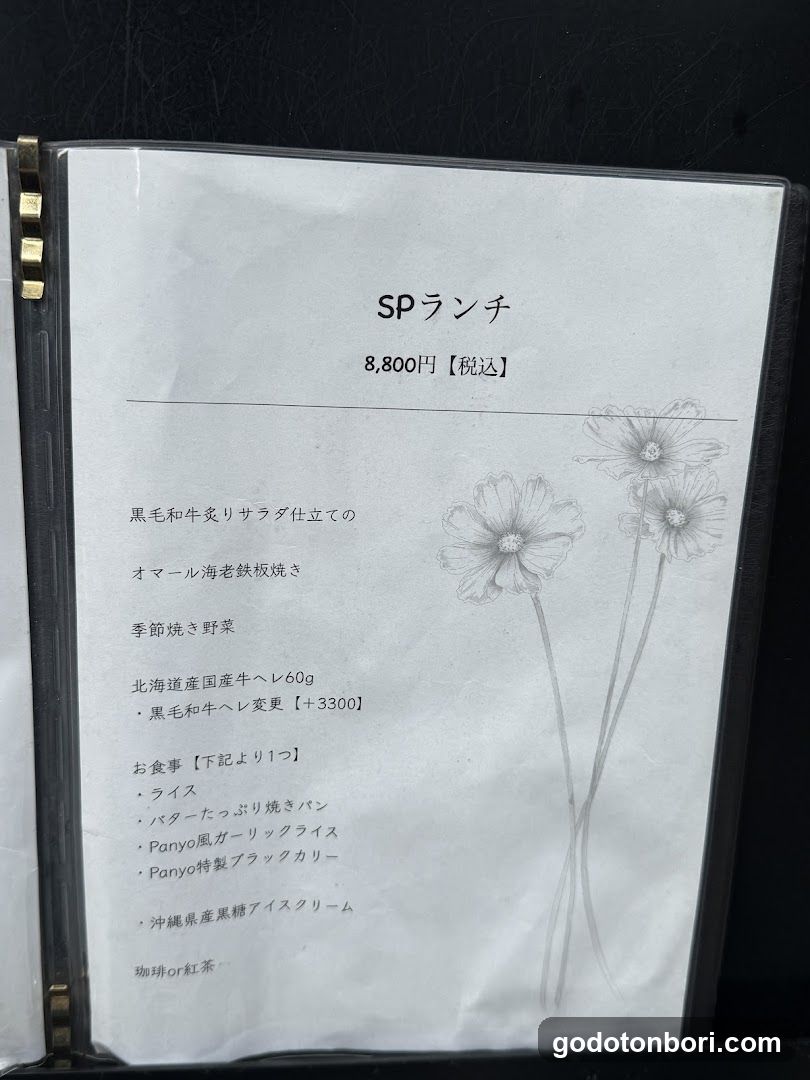 A printed menu page featuring a SP (Special) lunch option priced at 8,800 yen including tax. The menu includes items like Oamaru Sea Cucumber Grilled, Seasonal Stir-fried Vegetables, Hokkaido Domestic Beef Hele60g, and various bread options such as Butter Toasted Bread, Panyo Wind Garlic Raisin Bread, and Panyo Special Black Curry. It also lists Okinawa Black Sugar Ice Cream and Matcha or Red Tea.