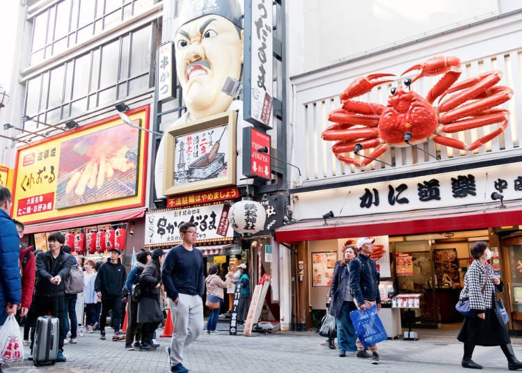 Giant 3D food signs including crab and pufferfish along Dotonbori canal in Osaka