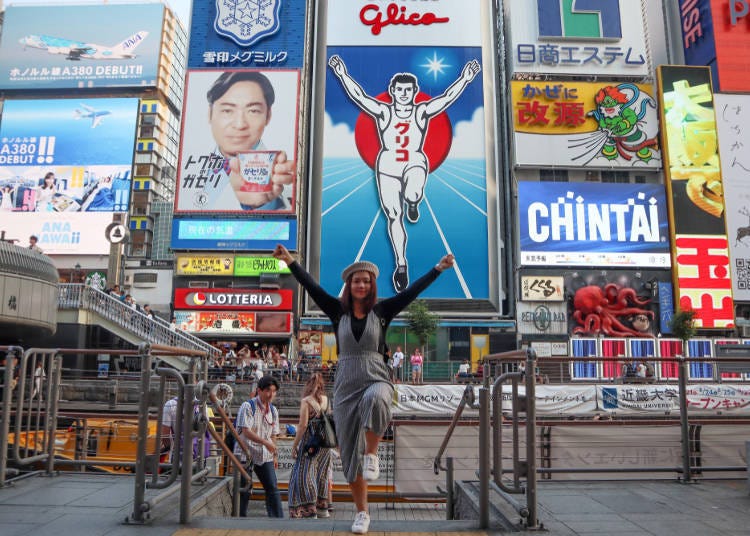 Tourists posing with the Glico sign from the Tombori River Walk in Dotonbori
